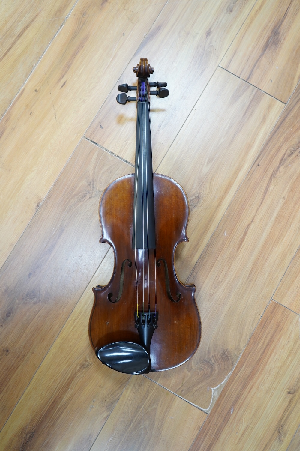 An early 20th century German violin, with a label reading ‘Copy of Joseph Guarnerius, Made in Germany’, body length 35.5cm, cased with a bow by Tourte. Condition - good.